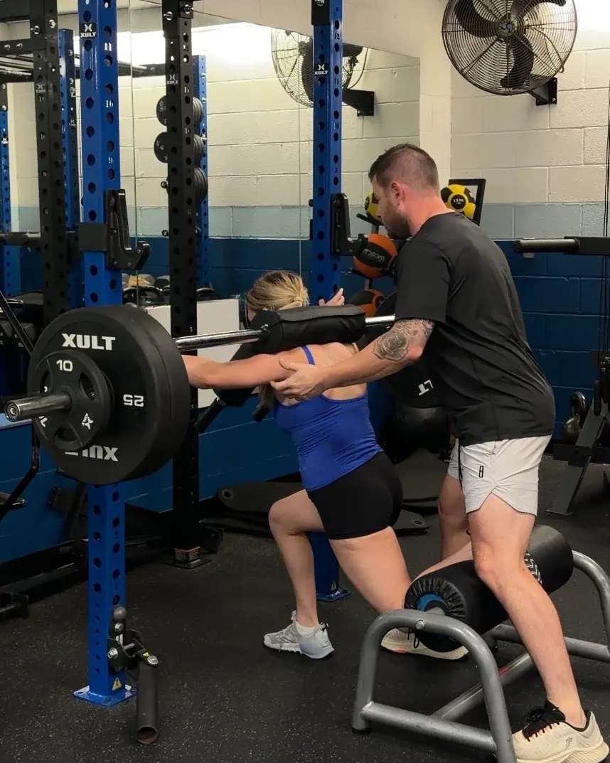 A coach guiding an athlete through a lift