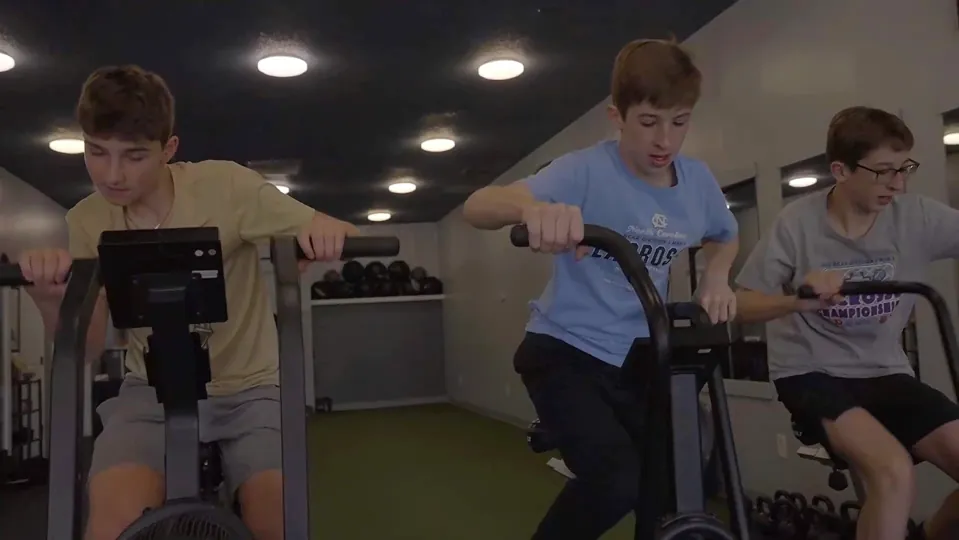 Athletes completing conditioning work on air bikes